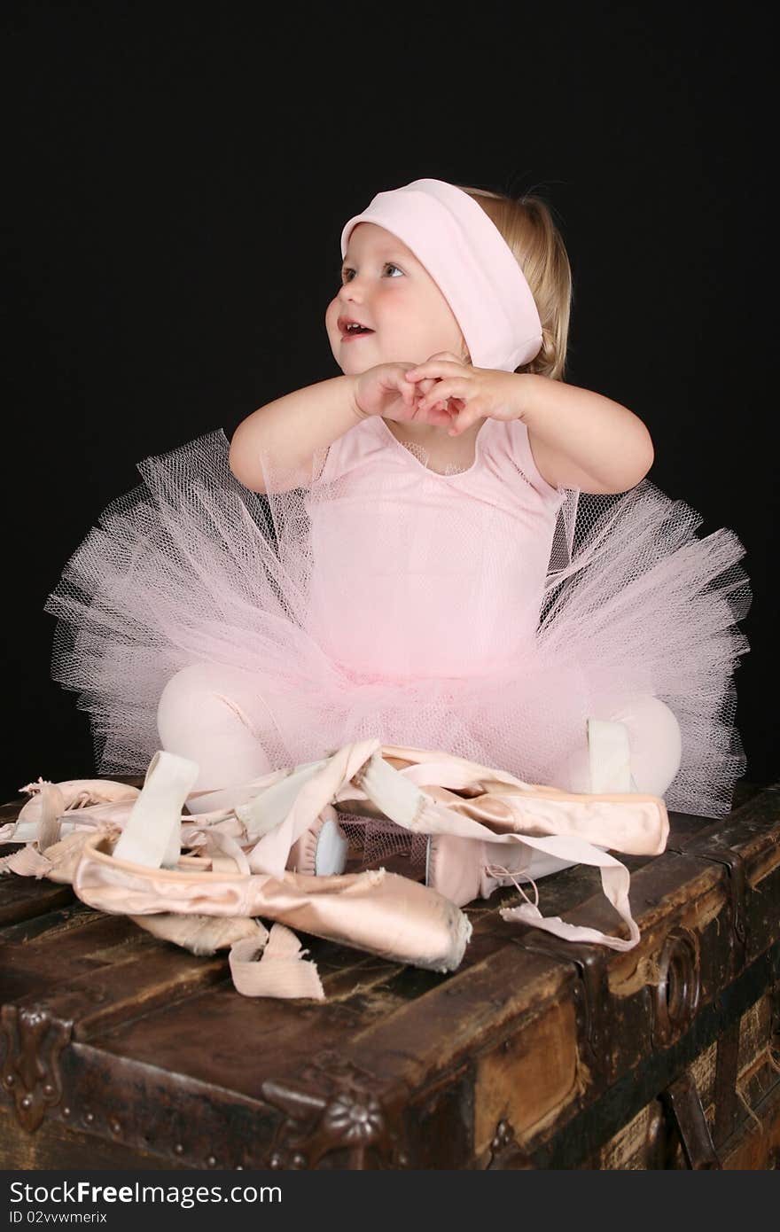 Baby ballerina sitting on an antique trunk