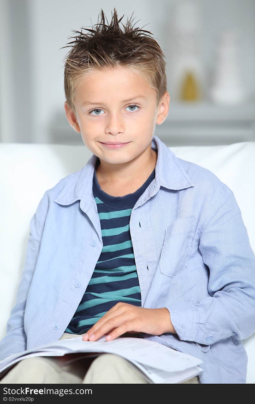 Blong little boy sitting on sofa with book. Blong little boy sitting on sofa with book