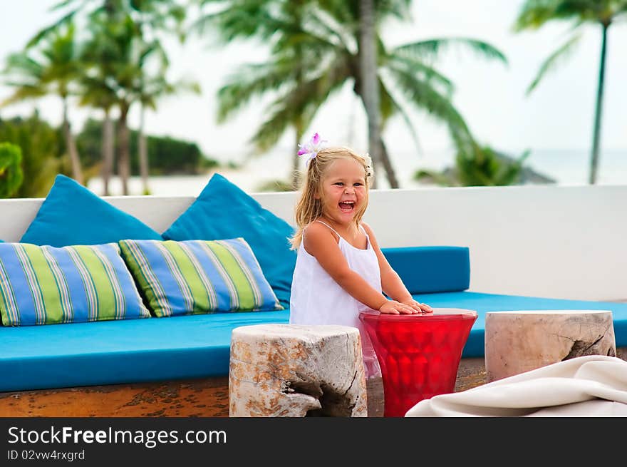 Happy toddler girl have a fun in beach cafe in exotic coastline background. Happy toddler girl have a fun in beach cafe in exotic coastline background