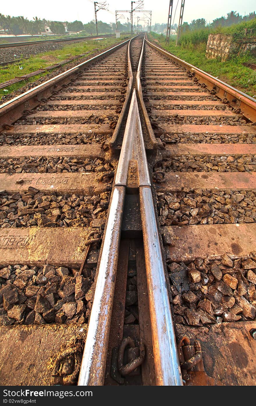 Railway tracks converging into one at a crossroad