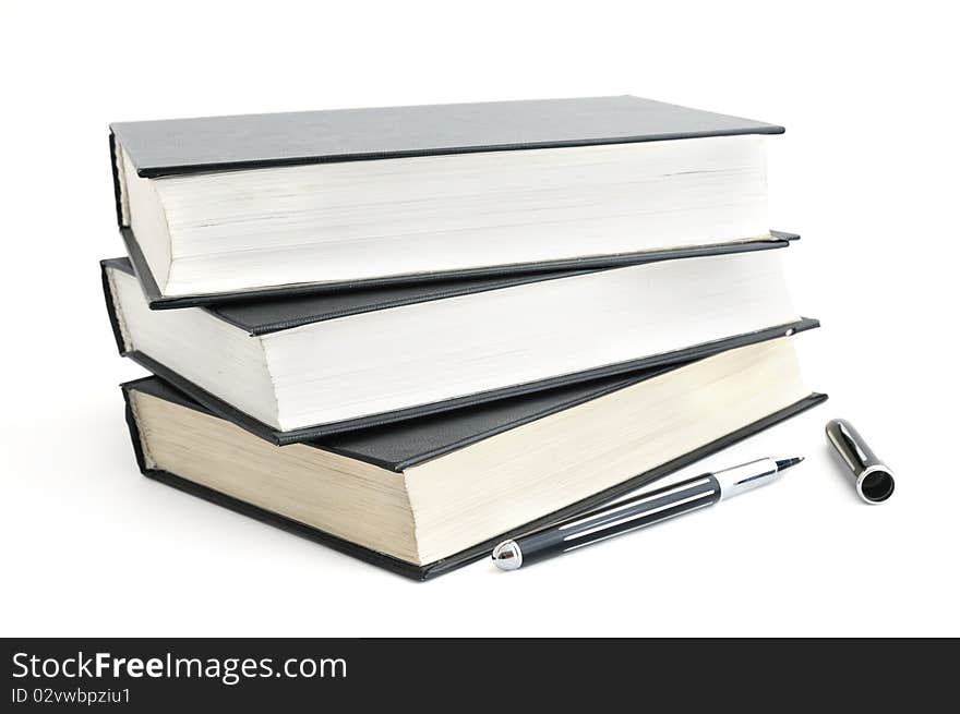 Stack of old books with black covers and a pen isolated on white. Stack of old books with black covers and a pen isolated on white