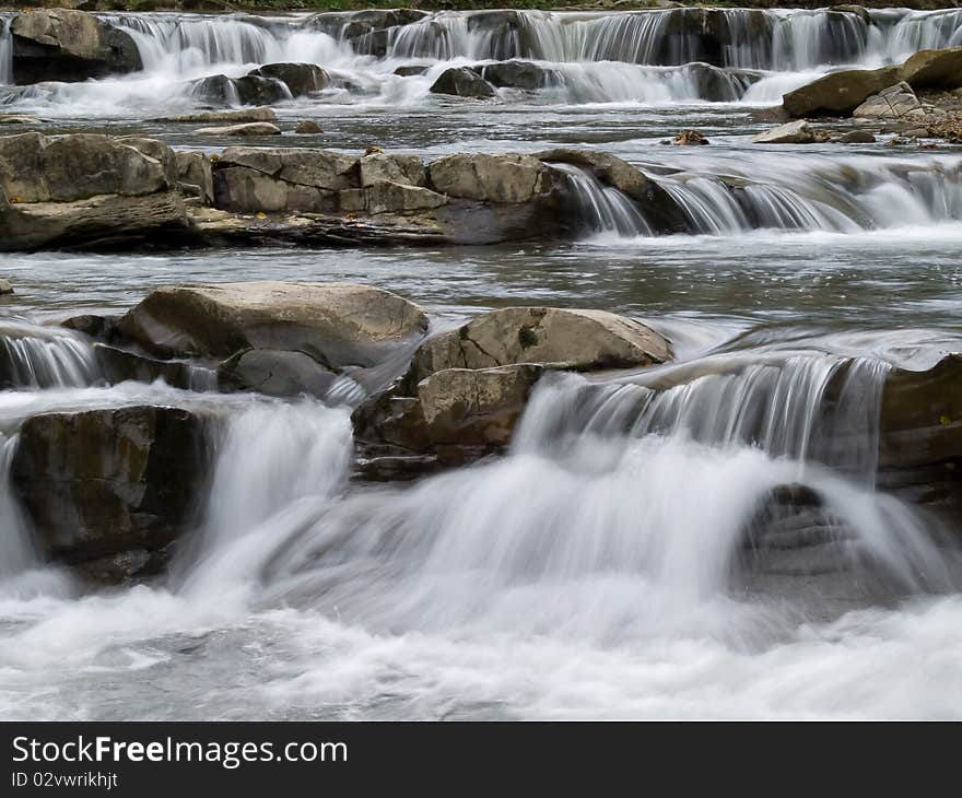Rapid stream flowing between the rocks. Rapid stream flowing between the rocks.