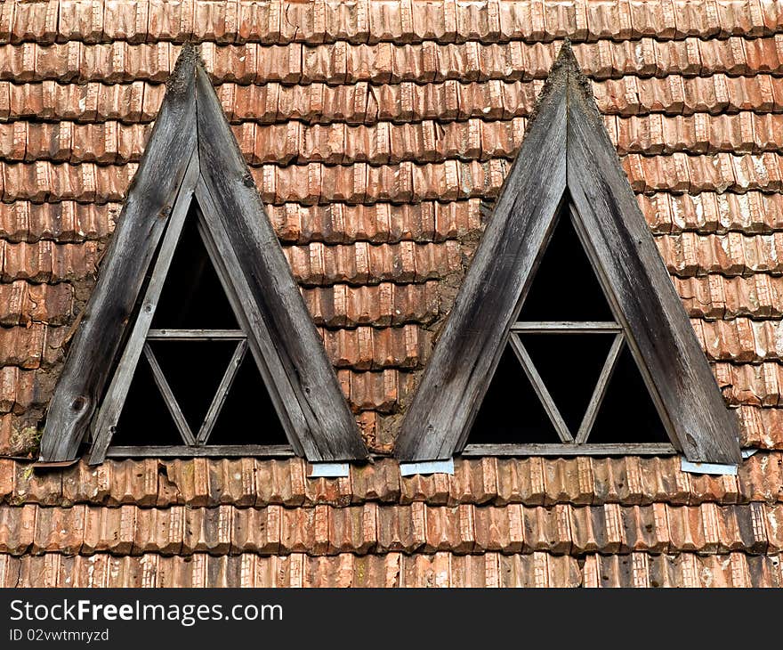 Old obsolete roof with red tile and triangular wooden window. Old obsolete roof with red tile and triangular wooden window.