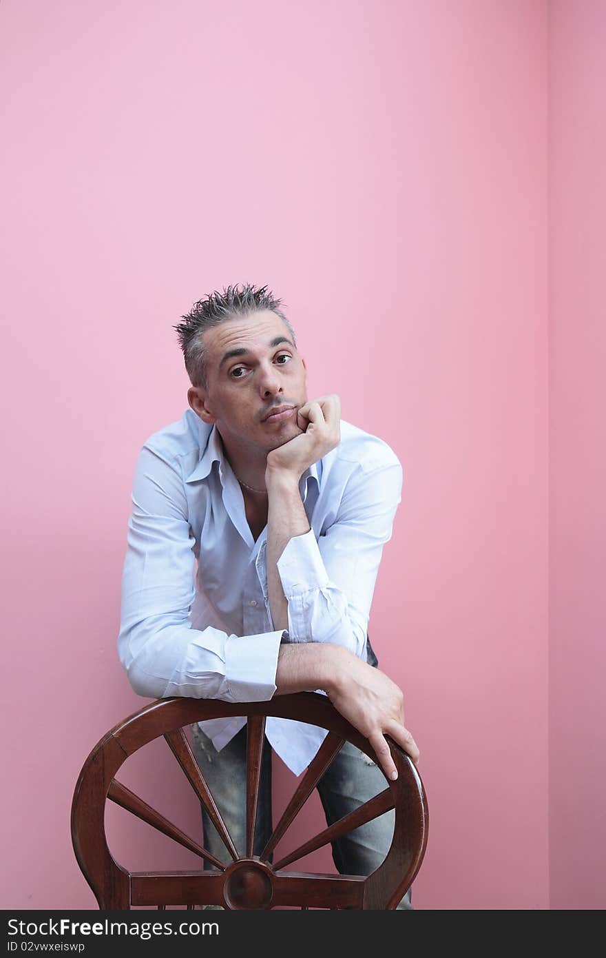 Man with blue shirt leaning on a wooden chair. Man with blue shirt leaning on a wooden chair