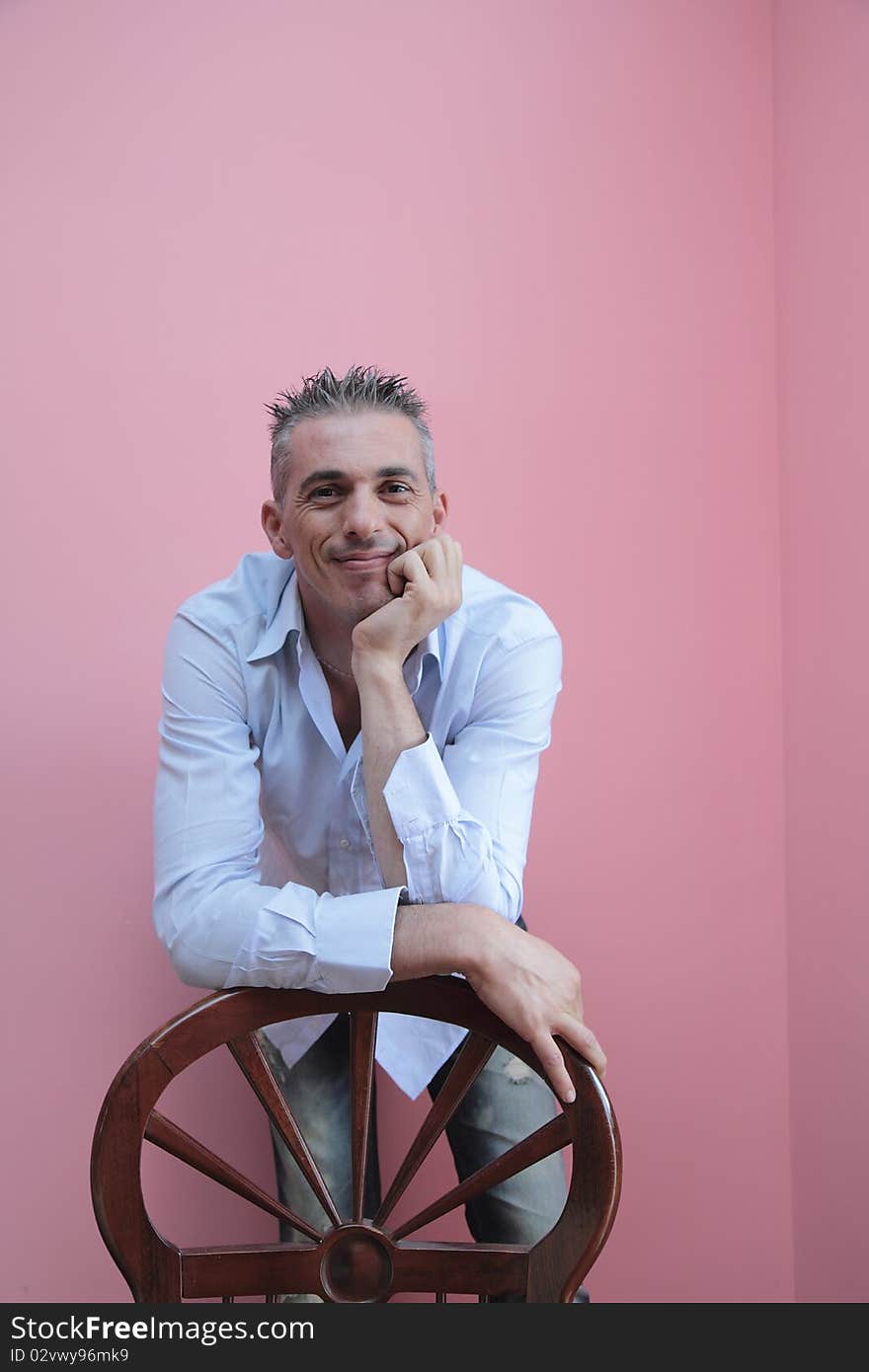 Man with blue shirt leaning on a wooden chair. Man with blue shirt leaning on a wooden chair