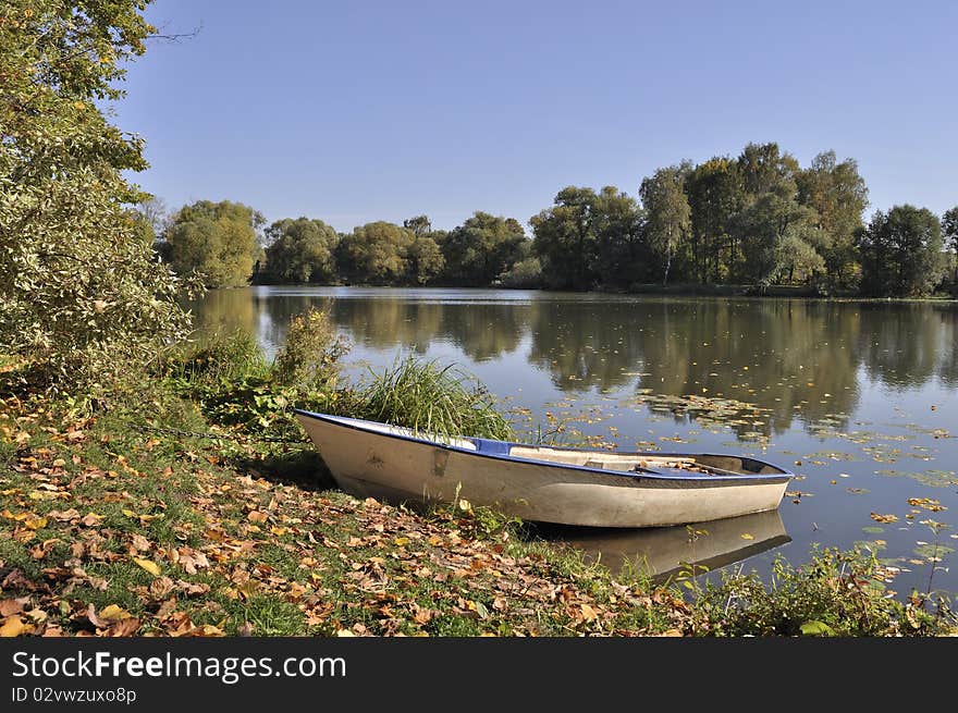 Boat on the lake bank in park, sunny autumn day. Boat on the lake bank in park, sunny autumn day