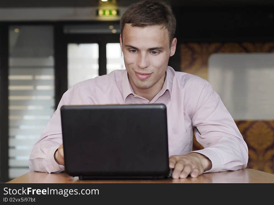 Smiling businessman  working behind the black laptop. Smiling businessman  working behind the black laptop
