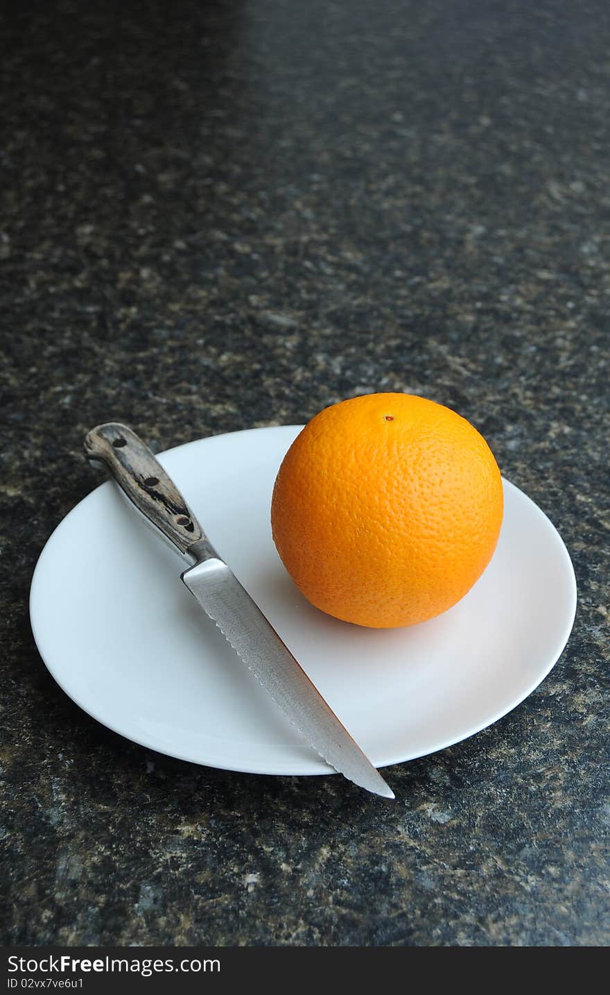 An orange fruit on a white plate with a knife. An orange fruit on a white plate with a knife