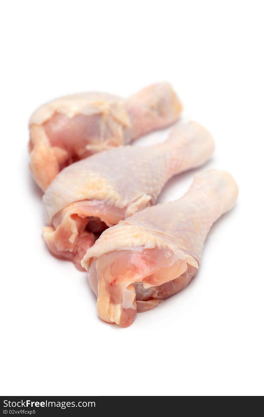 Close up of three raw chicken drumsticks isolated on white background.