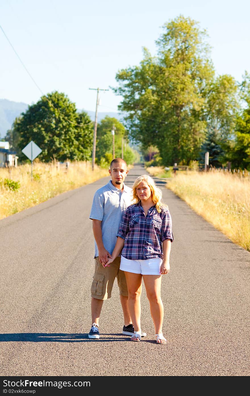 A young engaged couple poses outdoors for a romantic photo.