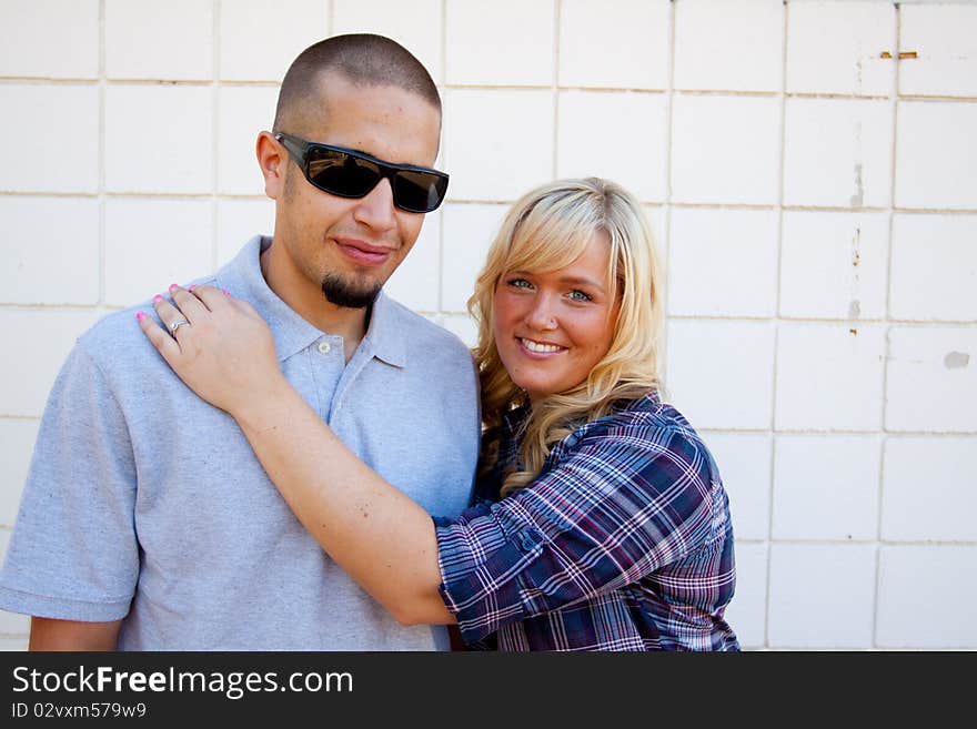 A young engaged couple poses outdoors for a romantic photo.