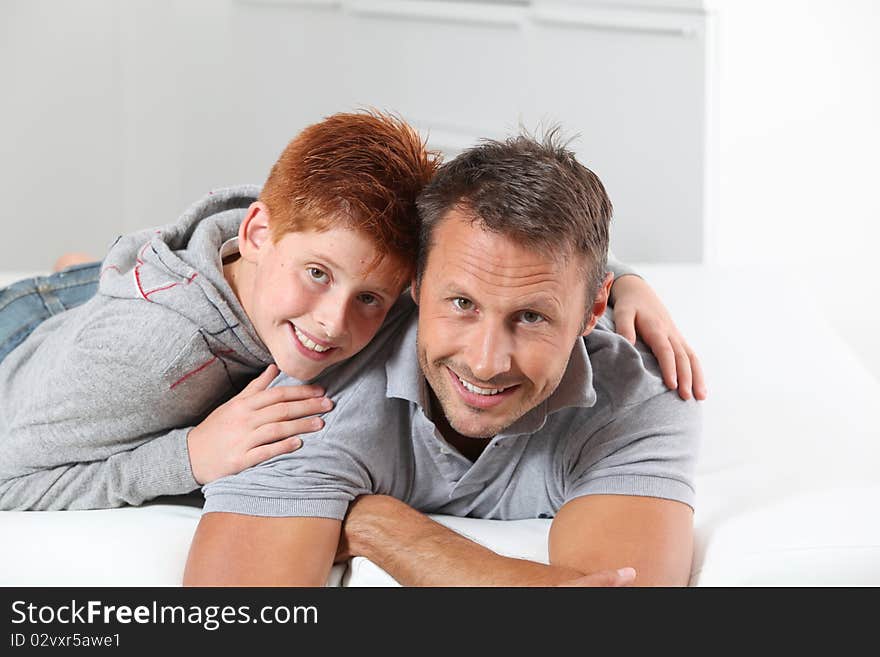 Man with child lying on a sofa at home. Man with child lying on a sofa at home