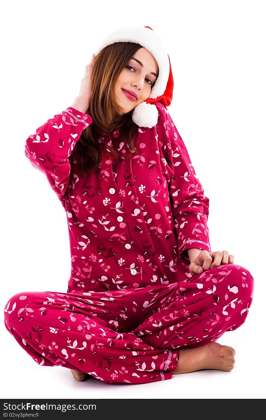 Front view of young lady posing with santa hat sitting on floor on an isolated background. Front view of young lady posing with santa hat sitting on floor on an isolated background