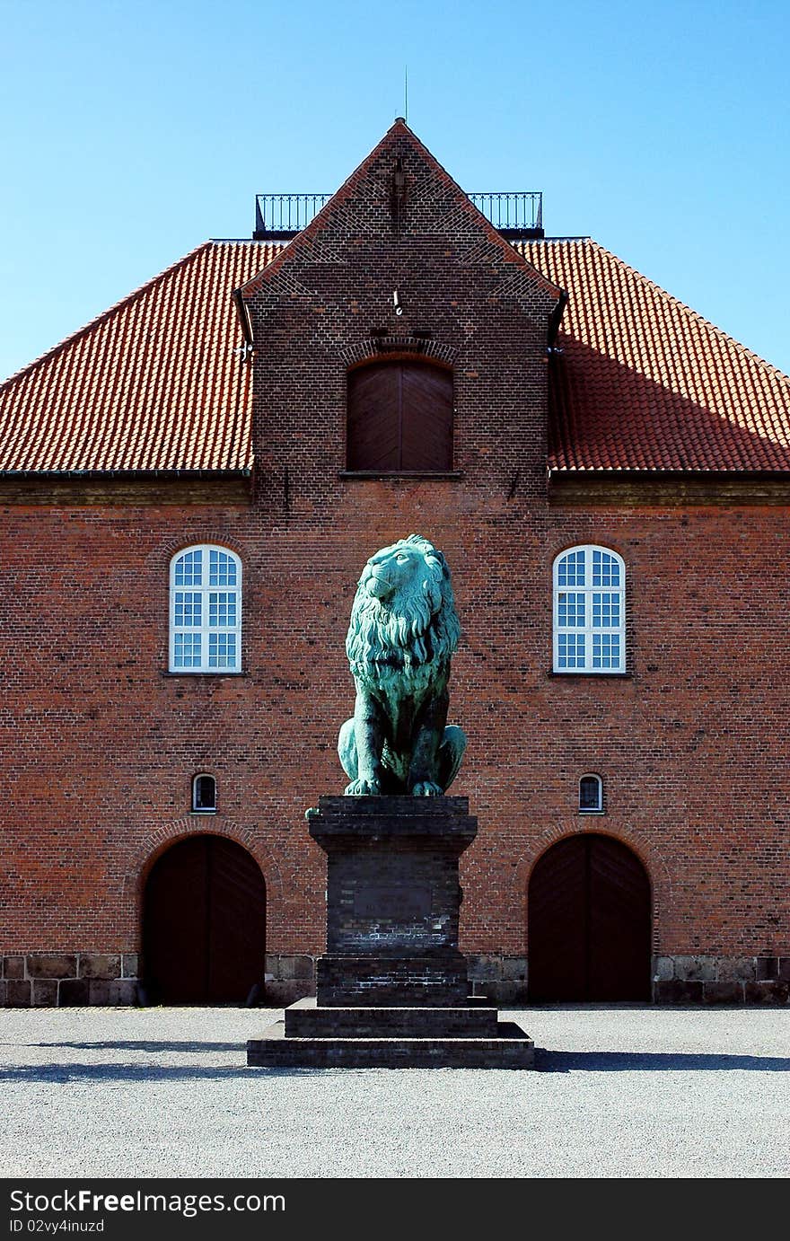 Old brick house in Copenhagen with copper statue of seated lion in front, Denmark. Old brick house in Copenhagen with copper statue of seated lion in front, Denmark