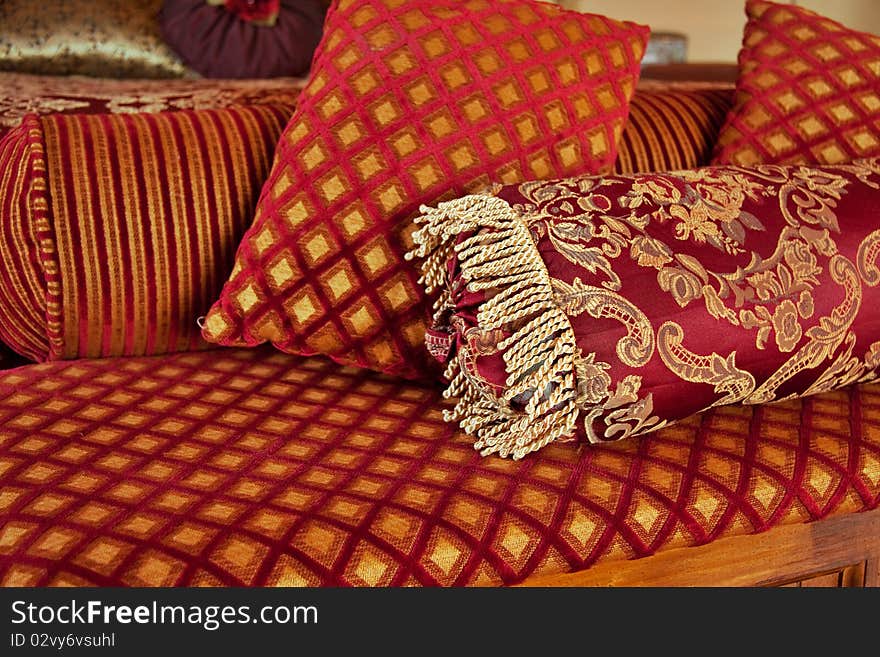 Red and gold cushions at end of bed in luxurious bedroom. Red and gold cushions at end of bed in luxurious bedroom