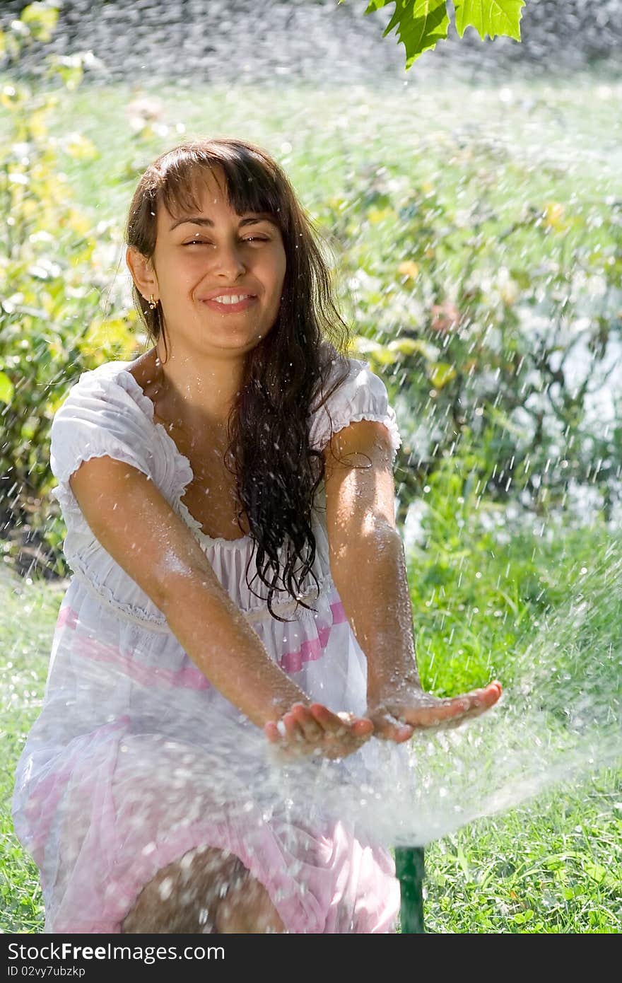 Pretty young lady having fun on the lawn amoung the sprinklers. Pretty young lady having fun on the lawn amoung the sprinklers