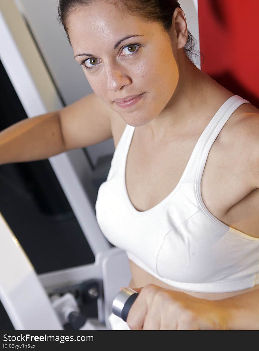 A caucasian woman uses a weight machine at the gym