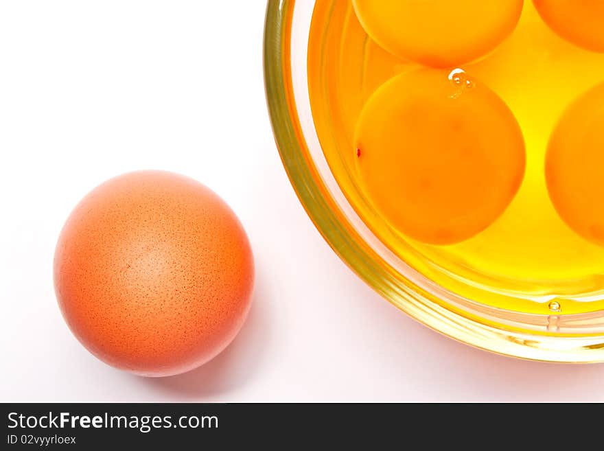 Yolks in a glass, and egg on white background.