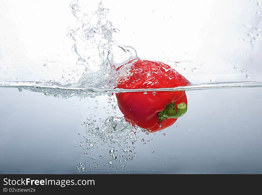 Fresh Red Bell Pepper splashing into water