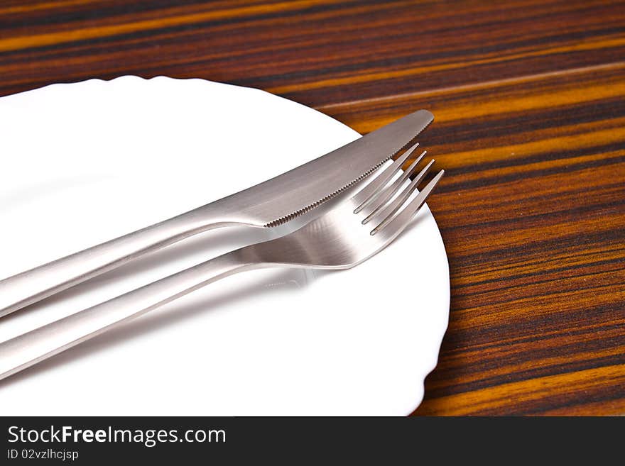 Aluminum fork and knife on a white plate. Aluminum fork and knife on a white plate