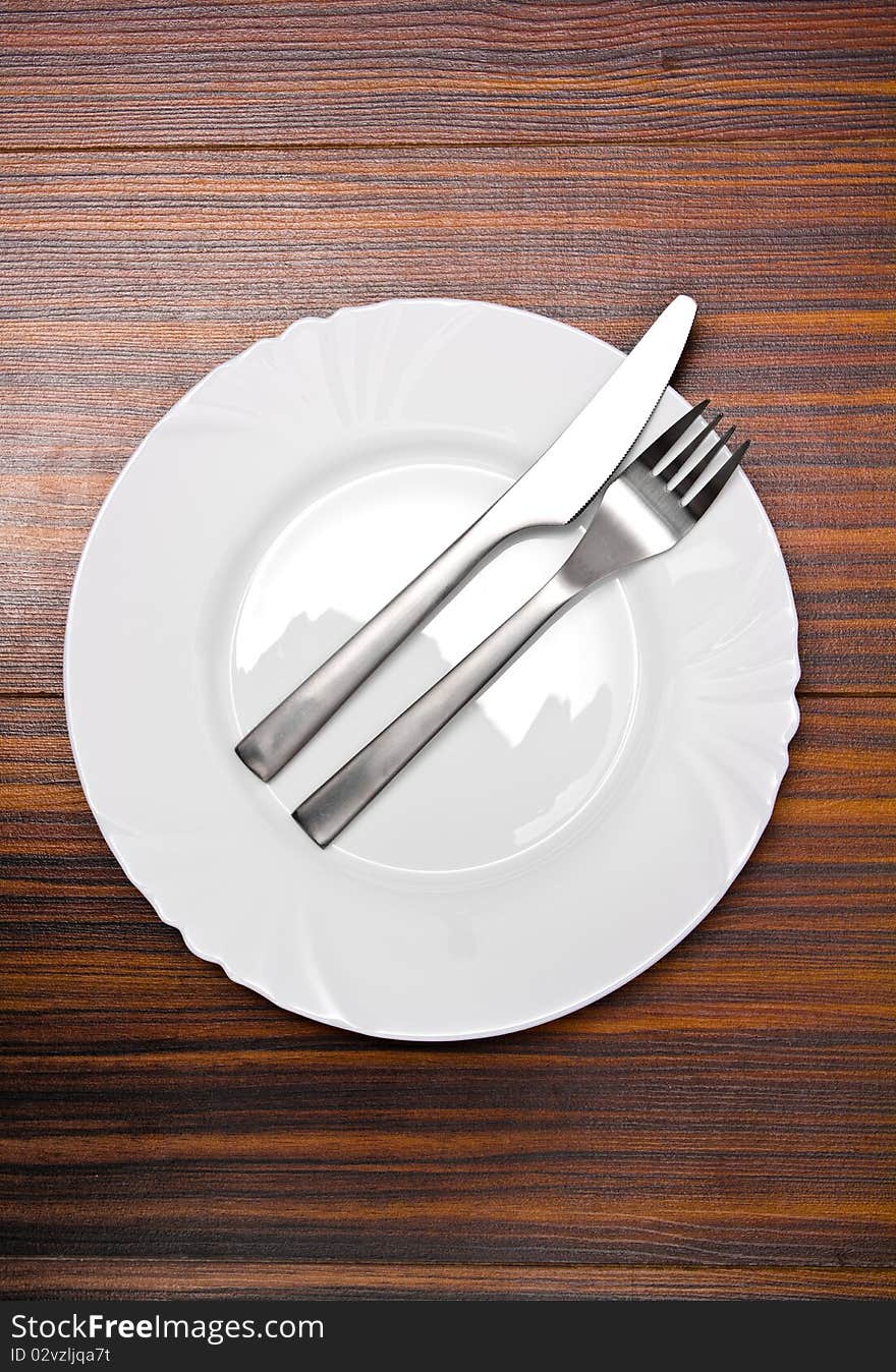 Aluminum fork and knife on a white plate. Aluminum fork and knife on a white plate