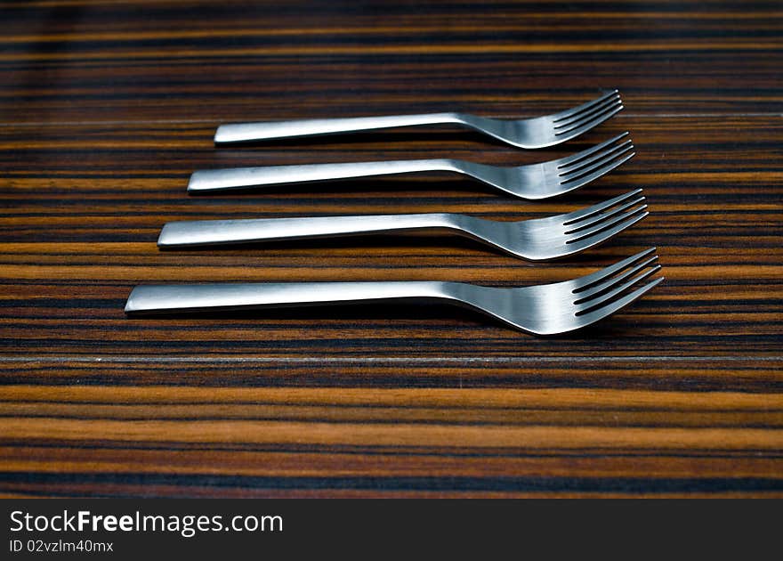 Blue Aluminum forks against the brown wood table. Blue Aluminum forks against the brown wood table