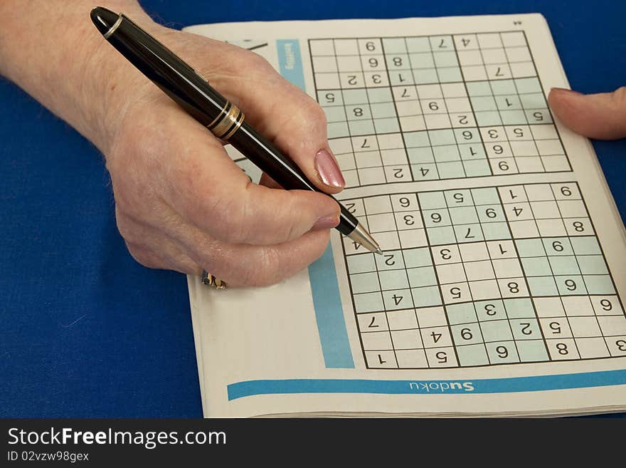 Elderly woman doing sudoku - isolated on white background. Elderly woman doing sudoku - isolated on white background