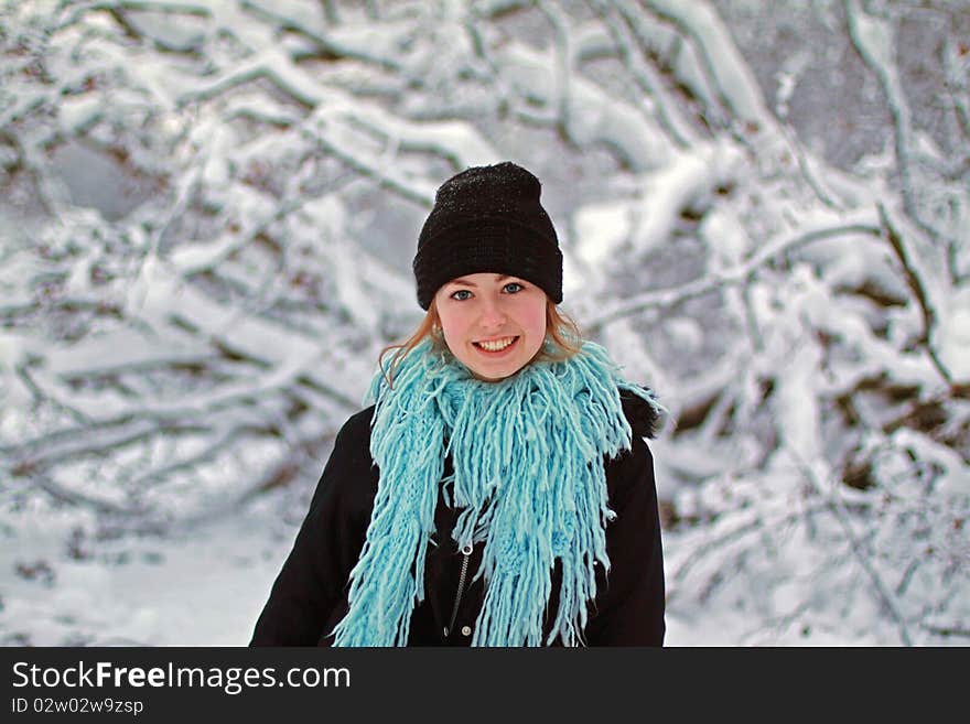 Girl in hat and scarf with snow covered tree in background. Girl in hat and scarf with snow covered tree in background