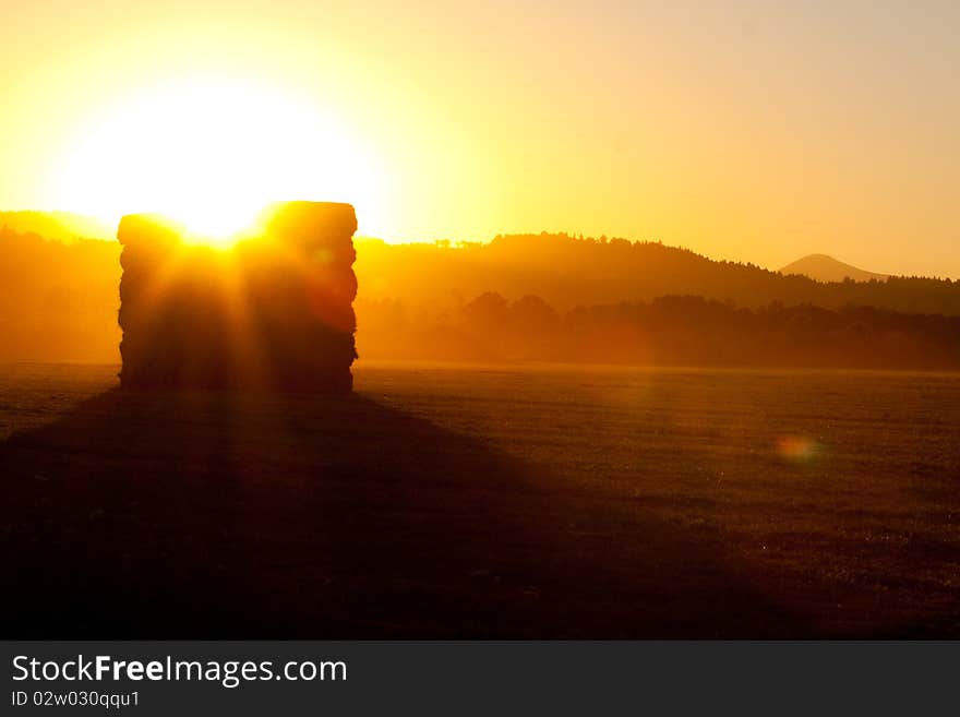 Stacks of hay bails are stacked up in a field on a ranch farm during sunset with a nice silhouette. Stacks of hay bails are stacked up in a field on a ranch farm during sunset with a nice silhouette.