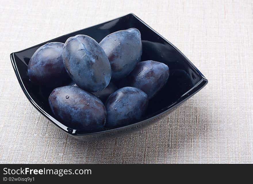 Black glass bowl with plums