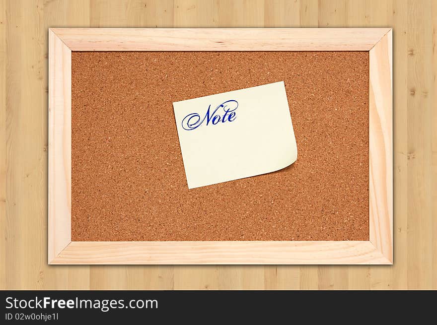 Corkboard with empty yellow notes on maple wood background