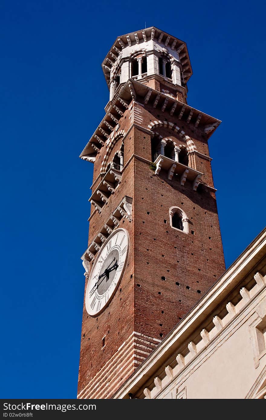 Lamberti tower in Verona isolated against a deep blue sky. Shows clock face