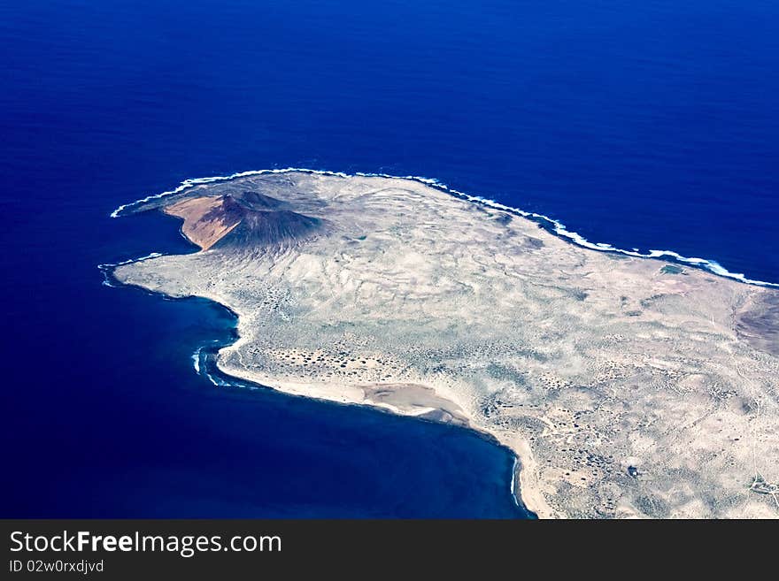 Aerial view of Lanzarote. Deep blue sea and a volcano with a desert landscape. Aerial view of Lanzarote. Deep blue sea and a volcano with a desert landscape