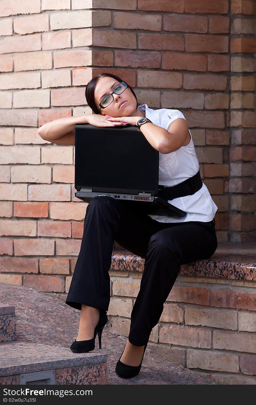 Businesswoman sitting with laptop agains brick wall of the office building. Businesswoman sitting with laptop agains brick wall of the office building