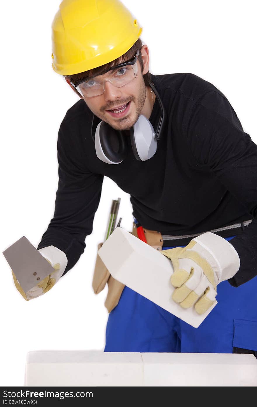 Happy bricklayer with stone and spade on white background