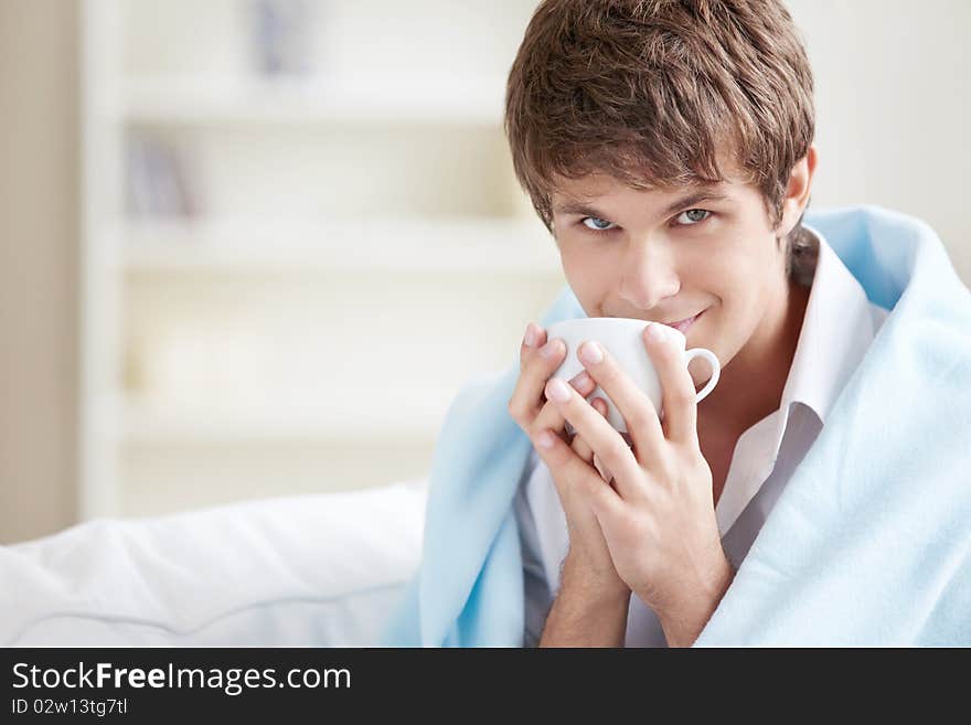 A young man in a plaid with a cup. A young man in a plaid with a cup