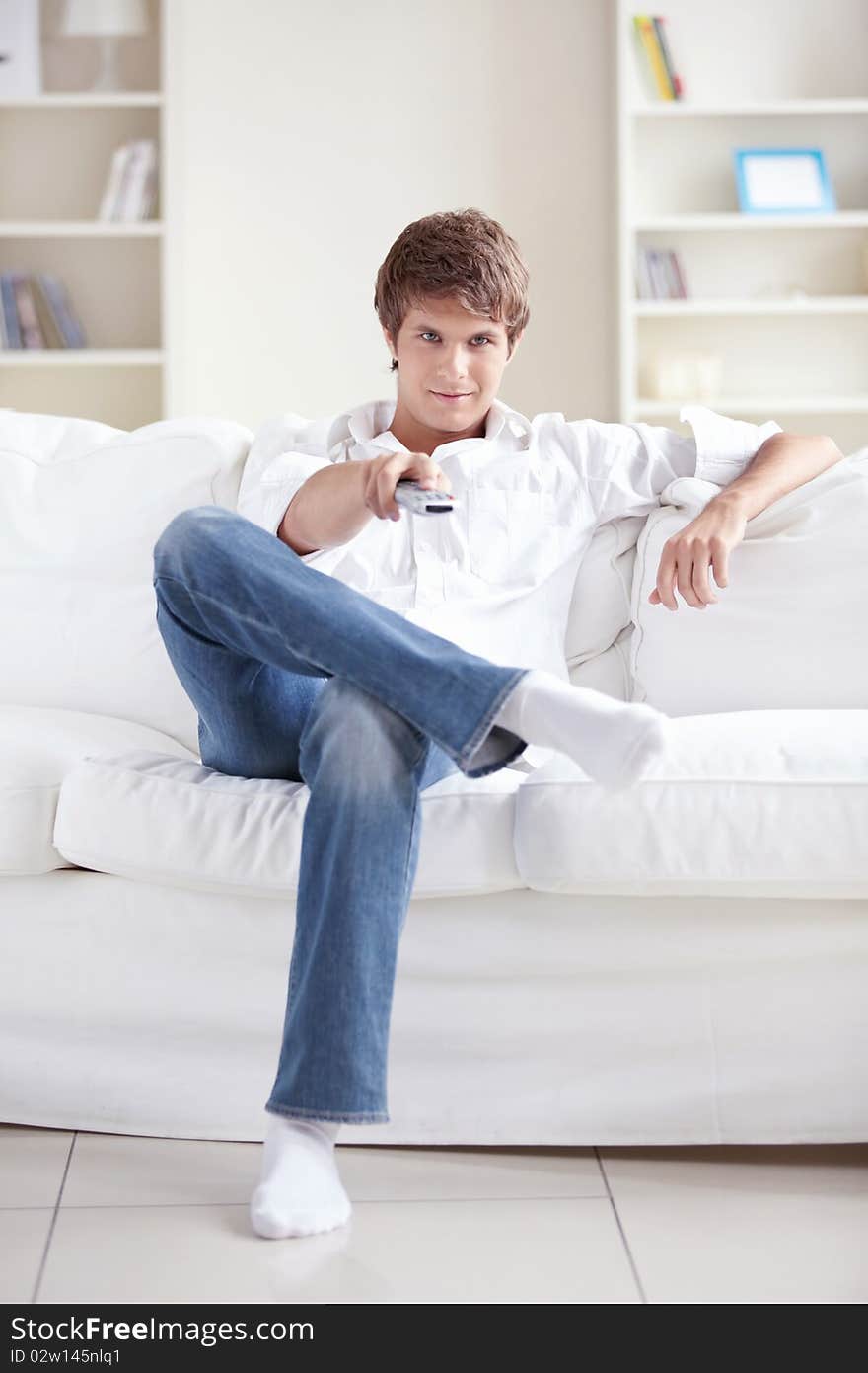 A young man watching TV on the couch. A young man watching TV on the couch