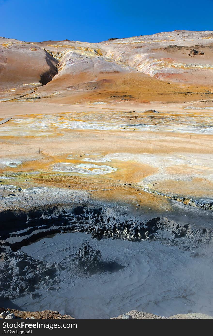 Bubble boiling mud with background of mountains of sulfur. Bubble boiling mud with background of mountains of sulfur