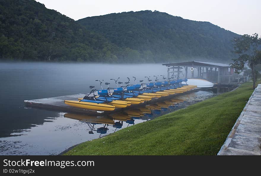 Water bikes moored at a boat dock in the early morning with a mild haze on the water