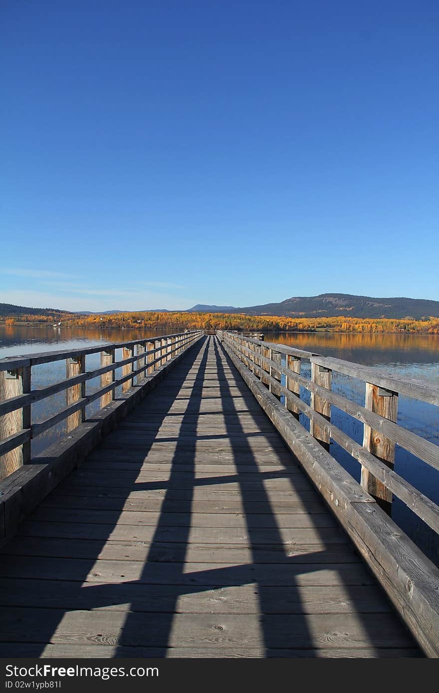 Long wooden Pier stretches into lake with autumn reflections. Long wooden Pier stretches into lake with autumn reflections