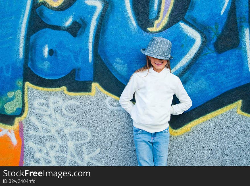 Fashionable stylish beautiful girl standing near a wall with graffiti. Outside. Fashionable stylish beautiful girl standing near a wall with graffiti. Outside