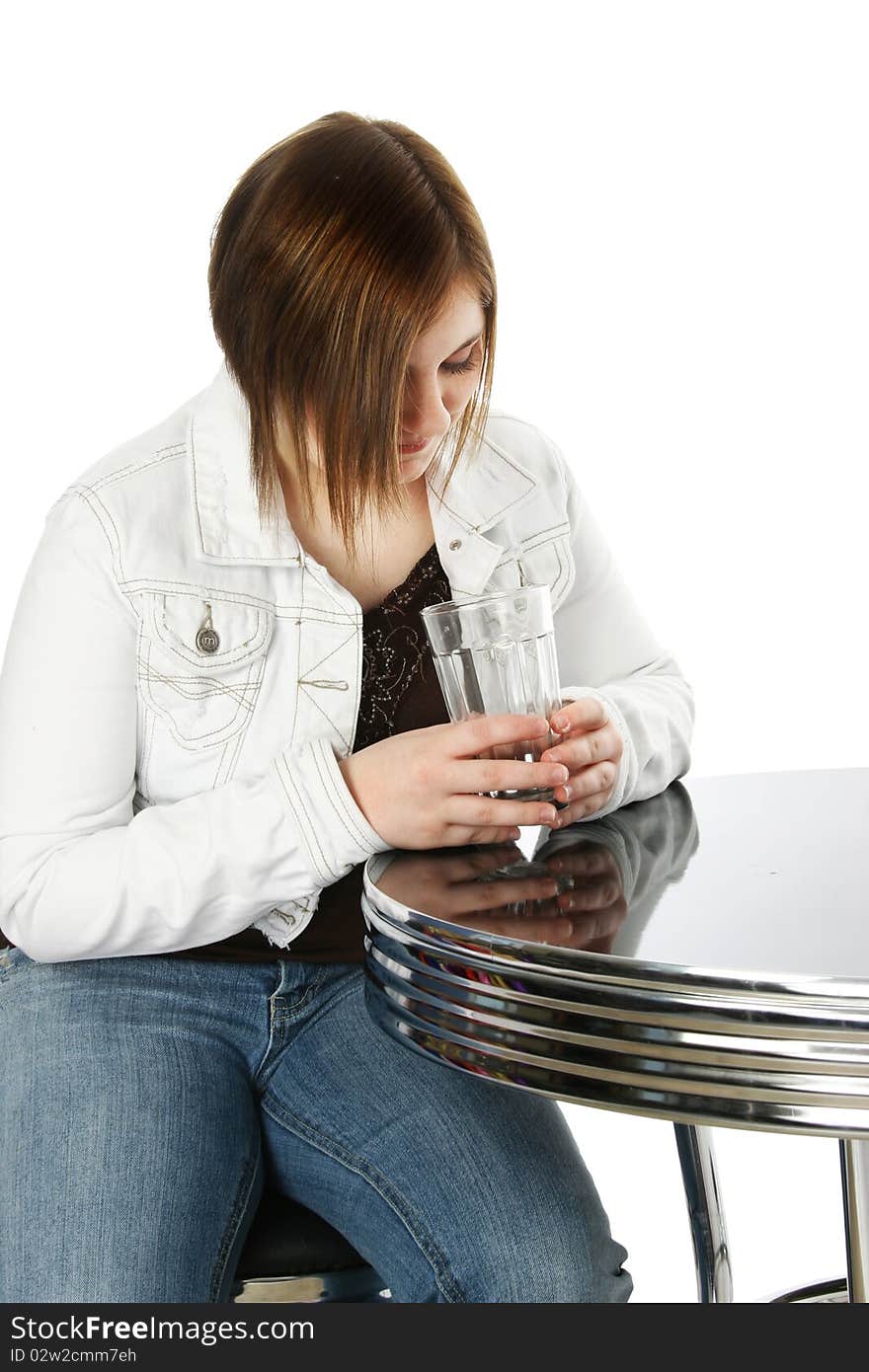 Teenager looking into bottom of empty glass over white.