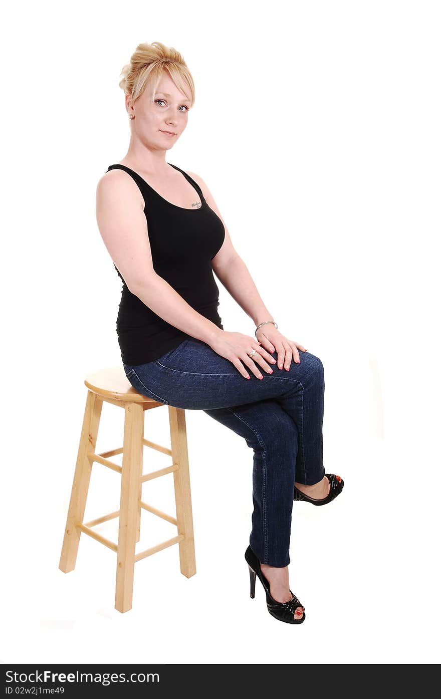 An pretty blond woman in jeans and a black tank top sitting in the studio, looking into the camera, for white background. An pretty blond woman in jeans and a black tank top sitting in the studio, looking into the camera, for white background.