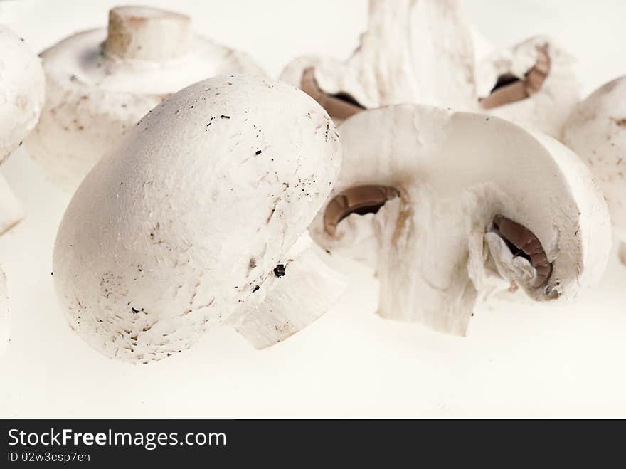 A bunch of brown champignons and a cut one on a white background