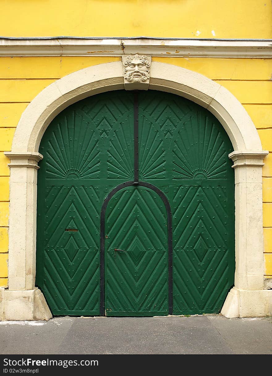 Old wooden door painted green, with carved stone frame and yellow wall. Old wooden door painted green, with carved stone frame and yellow wall