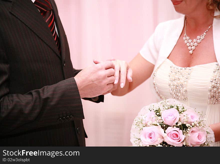 The groom puts on a ring to the bride in a registry office