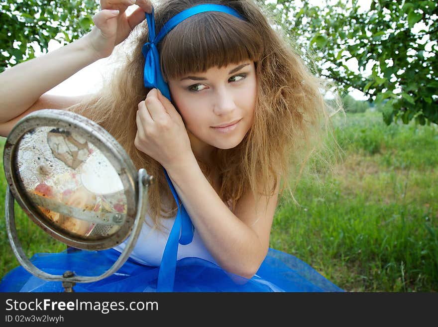 Beautiful girl looking to the circle shaped mirror in the garden. Beautiful girl looking to the circle shaped mirror in the garden