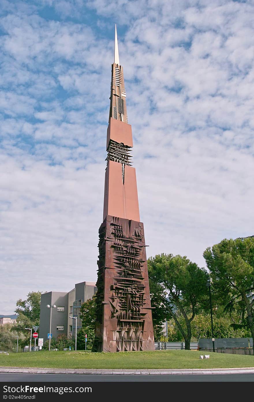 The work, Arrow of Light by Arnaldo Pomodoro, is an obelisk of steel with a triangular base weight of 105 tonnes divided into four sections. The artist has sought to unite in a single symbol the idea of technological developments, the historical importance that the steelworks had for the city of Terni and the reality of the hard work that, despite modern technological developments, it still he