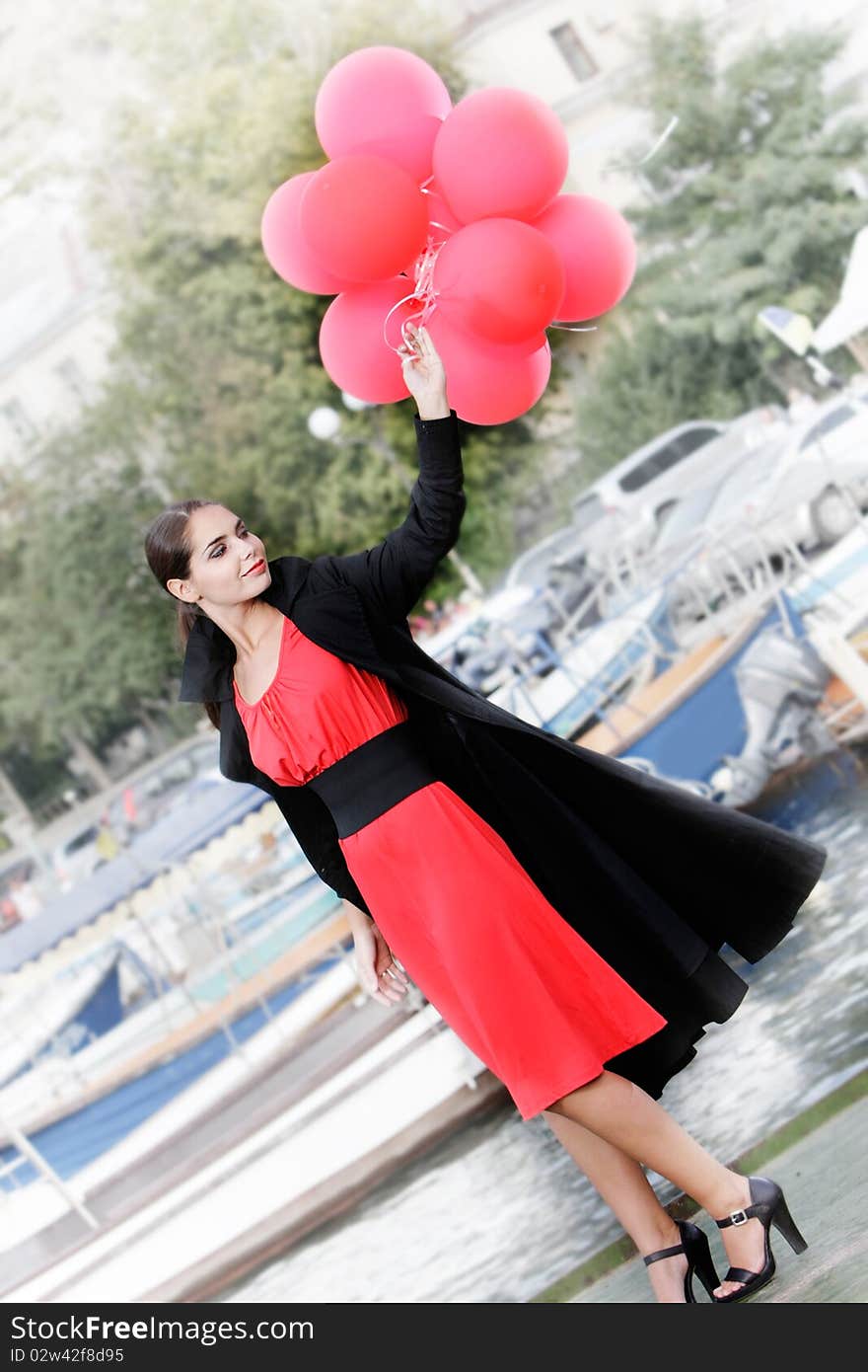 Young happy woman with red balloons on pier background