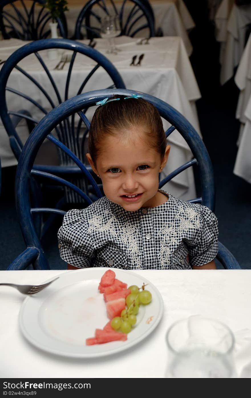 A sweet child sitting at table in a restaurant smiling. A sweet child sitting at table in a restaurant smiling